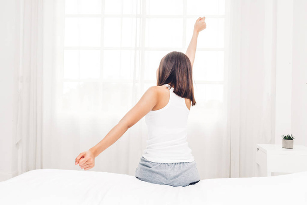 Woman sitting near the window and stretching in bed after wake up.Woman happy and relaxed breathing fresh air at morning - Foto, Imagem