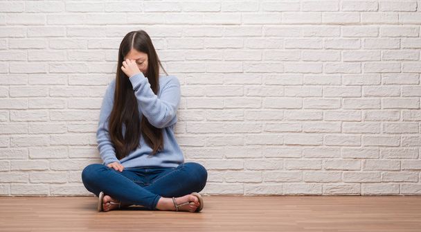 Giovane donna cinese seduta sul pavimento sopra muro di mattoni stanco sfregamento naso e gli occhi sensazione di stanchezza e mal di testa. Concetto di stress e frustrazione
. - Foto, immagini