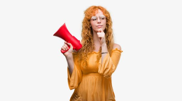 Jeune rousse femme tenant mégaphone visage sérieux penser à la question, idée très confus
 - Photo, image