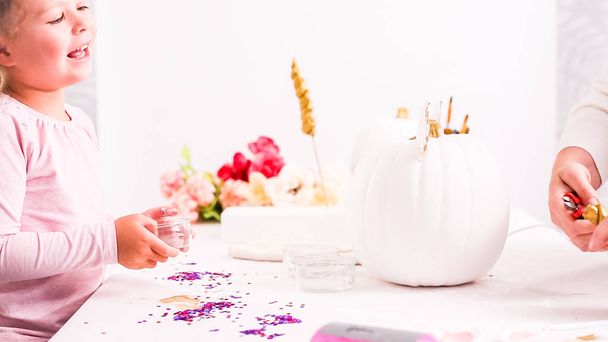 Mother and daughter decorating craft pumpkins with unicorn theme for Halloween. - Photo, Image