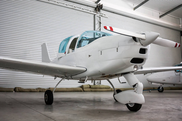 Avião esportivo pequeno com dossel aberto no hangar
 - Foto, Imagem