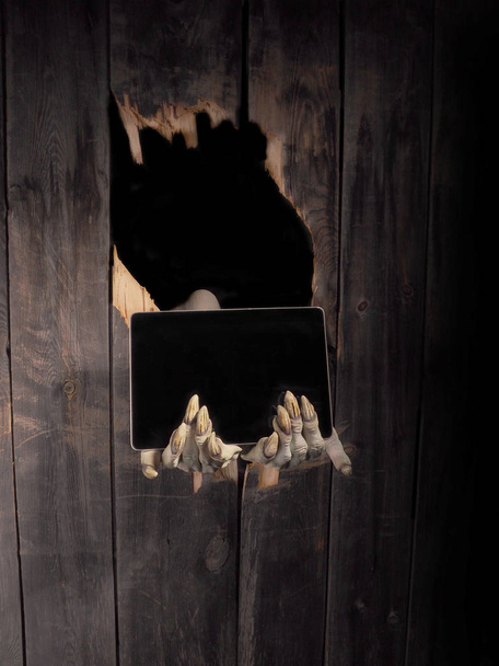 Zombie hand through hole cracked in rustic wood.Halloween theme - Φωτογραφία, εικόνα