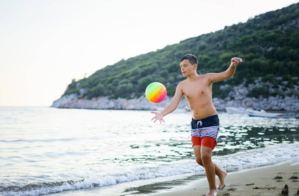 Jonge jongen te voetballen tegenover de zee tijdens de zomervakantie - Foto, afbeelding