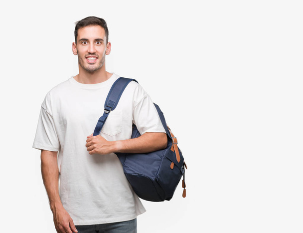 Handsome young man holding backpack with a happy face standing and smiling with a confident smile showing teeth - Фото, изображение
