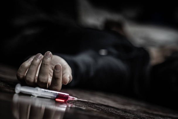 Джинсовий чоловік лежить на підлозі біля шприца для ін'єкцій наркотиків. Смерть від передозування наркотиками та концепції залежності
 - Фото, зображення