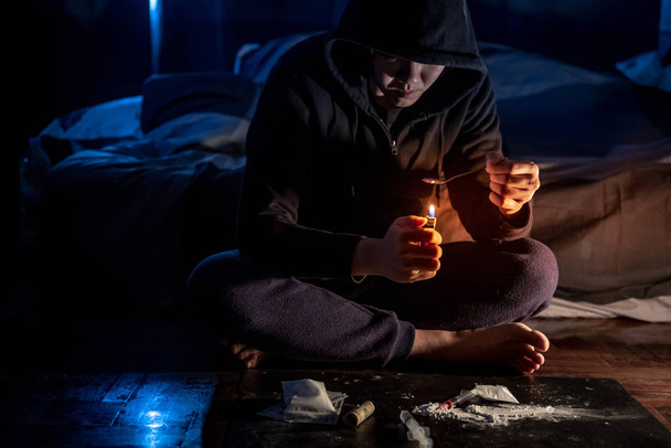 Hombre drogadicto preparando la dosis de heroína mediante el uso de cuchara y encendedor de cigarrillos para derretir, jeringa para inyección. Sobredosis de drogas duras y concepto de adicción
 - Foto, Imagen