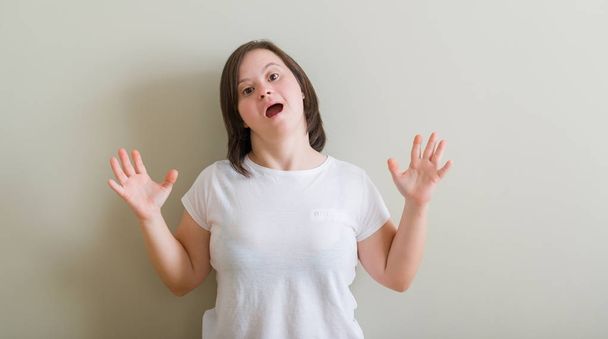 Женщина с синдромом Дауна, стоящая над стеной сумасшедшая, кричащая и кричащая с агрессивным выражением лица и поднятыми руками. Концепция разочарования
. - Фото, изображение