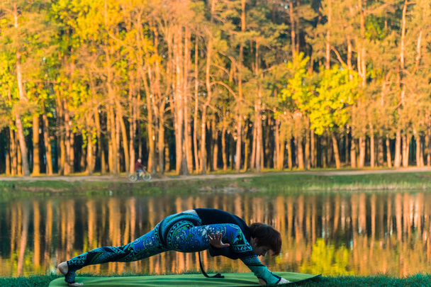Yoga. The girl in the park is practicing yoga - Φωτογραφία, εικόνα
