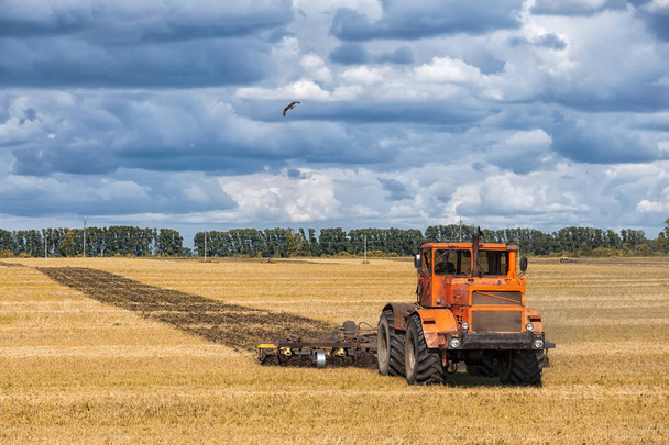 Un trattore arancio moderno aratura la terra i
 - Foto, immagini