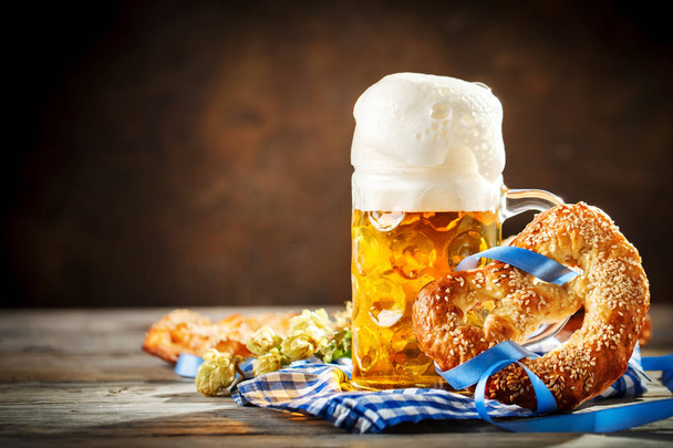 Tazas de cerveza y pretzels en una mesa de madera. Oktoberfest. Festival de la cerveza
. - Foto, imagen