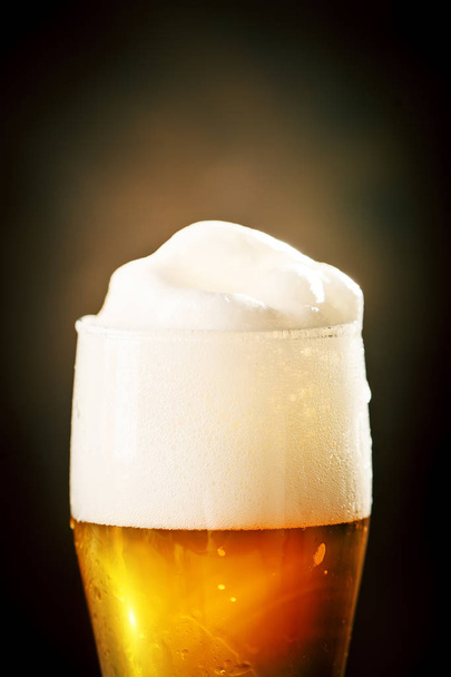 A glass of beer on a dark background. - Foto, afbeelding