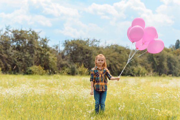 adorable child with pink balloons standing in summer field - Fotografie, Obrázek