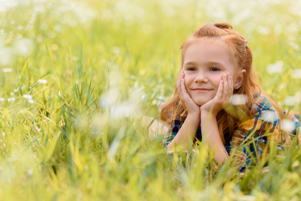retrato de un niño sonriente descansando sobre hierba verde en el prado
 - Foto, Imagen