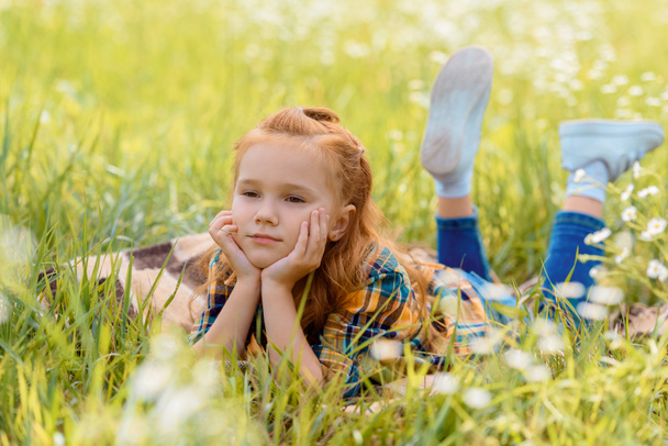 retrato de un niño pensativo descansando sobre hierba verde en el prado
 - Foto, imagen
