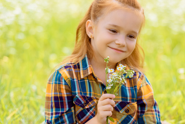 retrato de niño sonriente con ramo de flores silvestres en la mano
 - Foto, imagen
