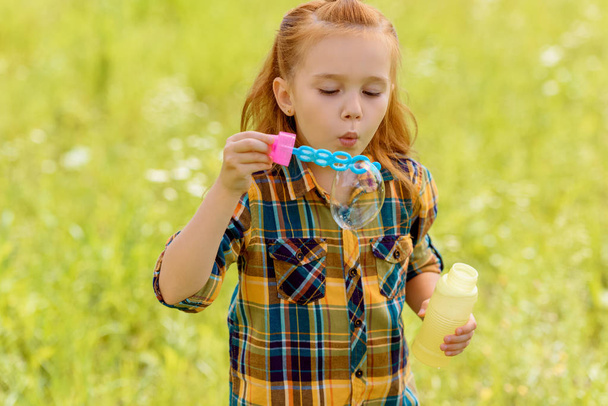 portrait of kid blowing soap bubbles in meadow - Foto, Imagem
