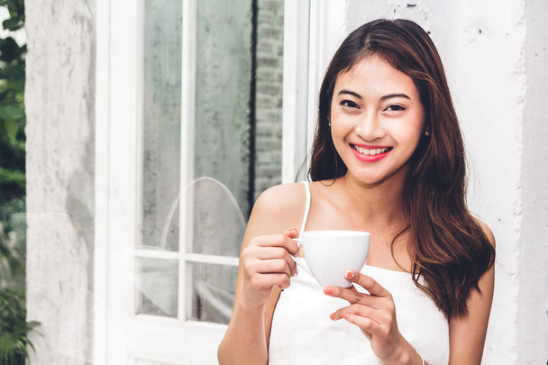 Beautiful young woman relaxing holding a cup of coffee in cafe - Photo, Image