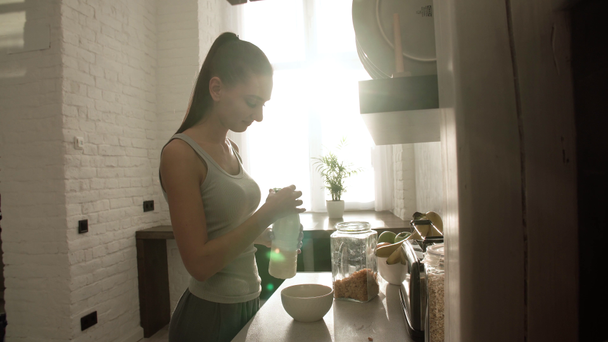 Жінка приготування пластівці з молоком на сніданок на світло кухні - Кадри, відео