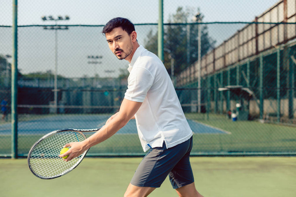 Giocatore di tennis determinato che guarda avanti con concentrazione prima di servire
 - Foto, immagini