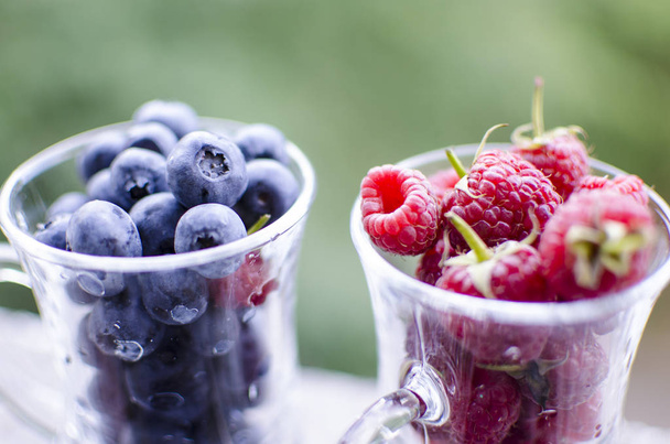A glass of sweet red raspberries and blueberries - Фото, изображение
