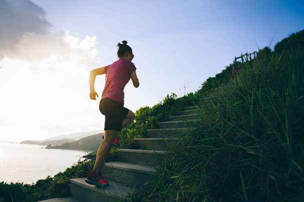 Determined woman running up on seaside mountain stairs - Photo, Image