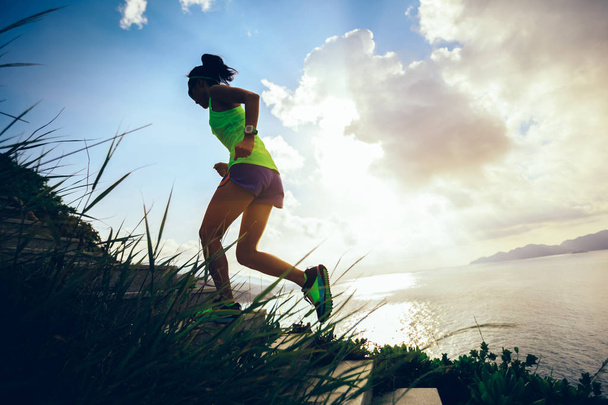 Determined woman running up on seaside mountain stairs  - Photo, image