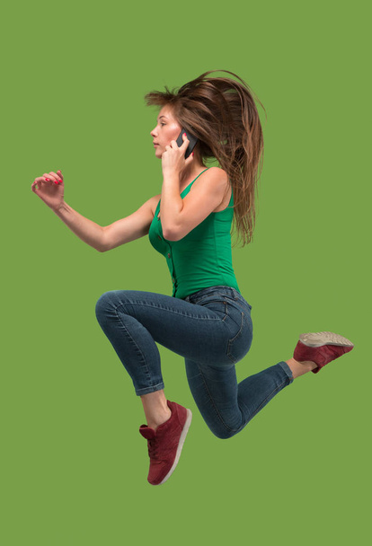 Comprimento total de mulher muito jovem com telefone celular enquanto salta
 - Foto, Imagem