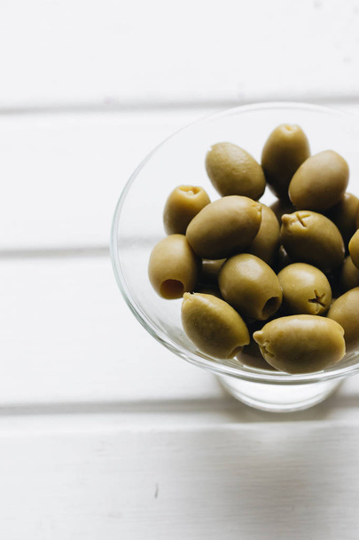 pile de délicieuses olives vertes dans un petit bol en verre sur fond blanc
 - Photo, image