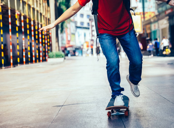 Skateboarder legs riding skateboard on city street - Photo, Image