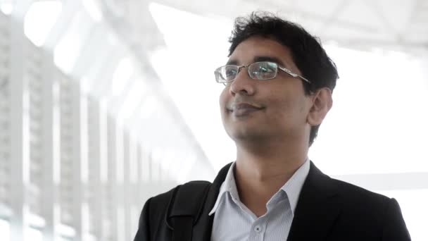 Portrait of a good looking smiling Indian businessman standing at modern building, with natural light. - Materiał filmowy, wideo