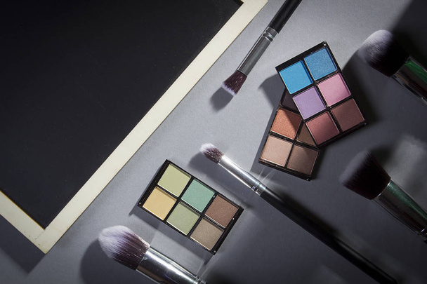 Cosmetic products and brushes for applying cosmetics on a gray background - 写真・画像
