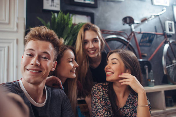 Ryhmä söpöjä teini-ikäisiä, jotka ottavat selfien matkapuhelimella istuessaan ravintolassa, jossa on retro-tyyli
 - Valokuva, kuva