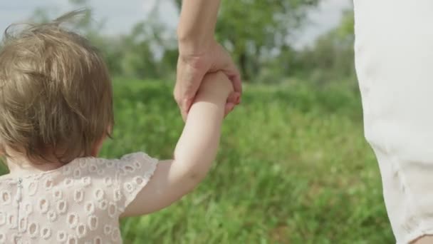 Zwolnionym tempie, Close Up, Dof: Cute happy baby dziewczyna trzymając się za ręce z młoda matka i co pierwsze kroki w miejscowym parku na idealne słoneczny letni dzień. Niesamowite mama wesoły córka uczy się chodzić - Materiał filmowy, wideo