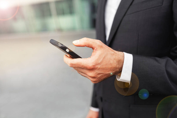 Close up of a man using mobile smart phone. Business and information technology concept. standing street with city in the background - Foto, Imagem