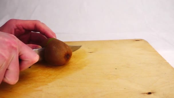 Cutting kiwi with a knife on a wooden board - Filmagem, Vídeo