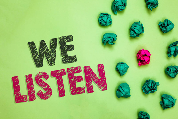 Текстовый знак "Мы слушаем". Концептуальные фото Группа людей, которые готовы услышать все, что вы хотите сказать скомканные морщинистые бумаги один другой розовый уникальный специальный зеленый фон
 - Фото, изображение
