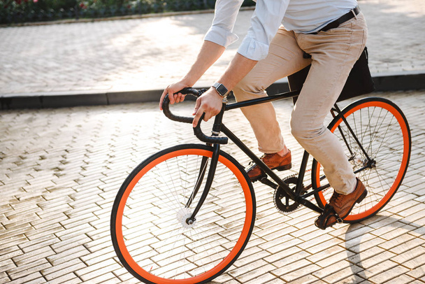 Cropped image of young man dressed in shirt riding on a bicycle on a city street - Photo, image