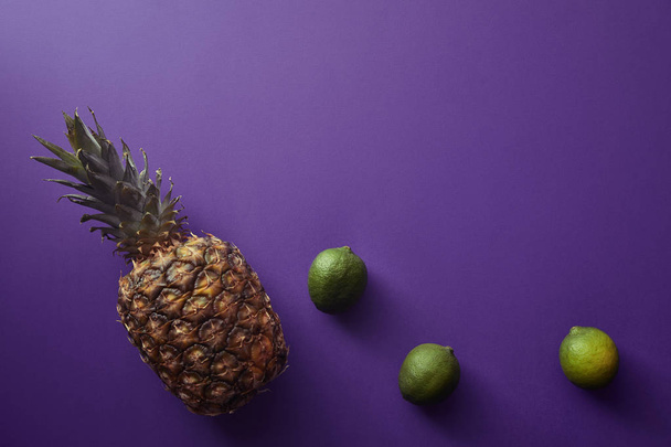 vue de dessus de l'ananas et des citrons verts sur la surface violette
 - Photo, image