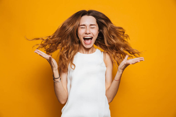 Portrait of a joyful young girl screaming isolated over yellow background - Foto, Imagem