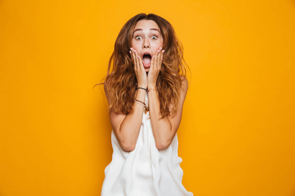 Portrait of a shocked young girl screaming isolated over yellow background - Fotó, kép
