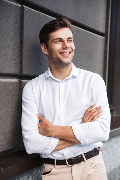 Portrait of a smiling young formal dressed man leaning on a wall outdoors - Foto, Imagem