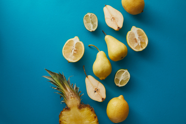 elevated view of pineapple, pears and lemons on blue surface - Photo, Image
