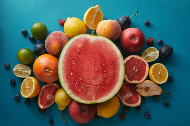 bovenaanzicht van watermeloen en andere verschillende vruchten op blauwe ondergrond - Foto, afbeelding