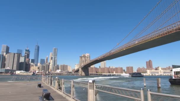 Nízký úhel pohledu: Kultovní pohled na Brooklyn Bridge a vysoce moderní mrakodrapy města Lower Manhattan od trajektového přístaviště. Brooklynský most spojující Brooklyn čtvrť a na Manhattanu v New York City - Záběry, video