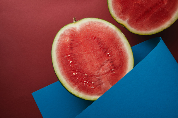 vista superior da melancia de corte e papel azul na superfície vermelha
 - Foto, Imagem