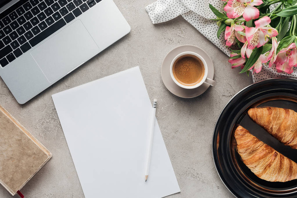 top view of cup of coffee with blank paper, croissants and laptop on concrete surface - Foto, Imagem