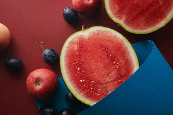 top view of fruits and blue paper on red surface - Photo, Image