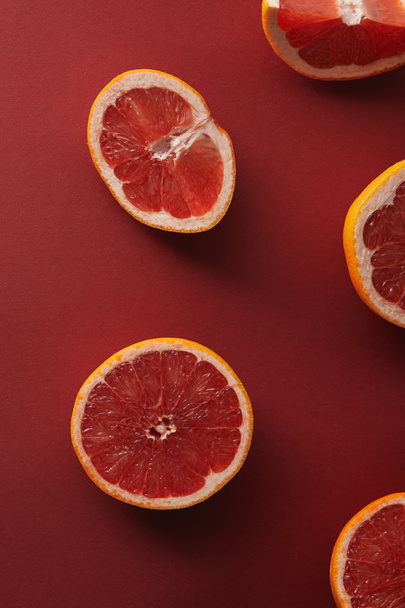 erhöhte Sicht auf geschnittene Grapefruits auf roter Oberfläche - Foto, Bild