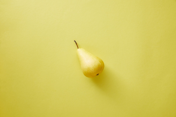 top view of one pear on yellow surface - Фото, изображение