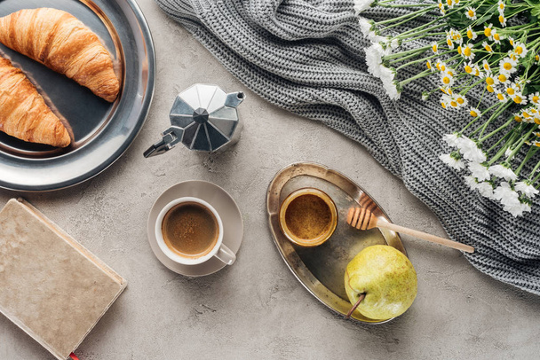 Draufsicht auf Tasse Kaffee mit Honig, Birne und Croissants auf Betonoberfläche - Foto, Bild